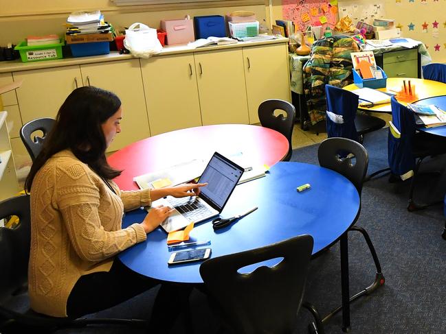 A teacher is seen in an empty class room at a primary school in Melbourne's inner north, Monday, March 23, 2020. Victorian Premier Daniel Andrews has brought forward school holidays as a measure to slow the rapid spreading Covid-19 virus throughout the state. (AAP Image/James Ross) NO ARCHIVING