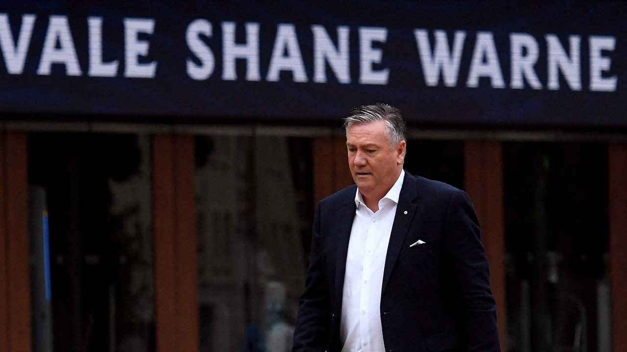 Eddie McGuire walks past a ‘Vale Shane Warne’ sign at the MCG.