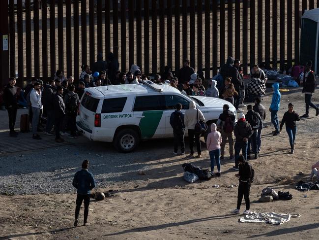 Migrants gather around a US border patrol vehicle between border fences waiting to be processed by US authorities, as seen from Tijuana, Baja California State, Mexico. Picture: AFP