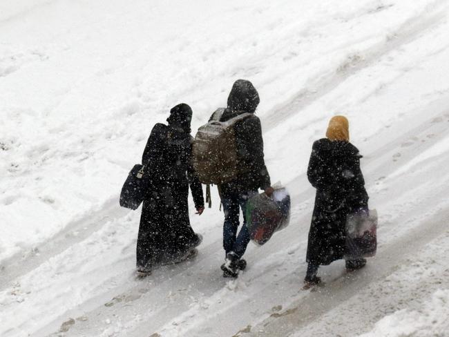 Syrians walk in a snow-covered street in the town of Maaret al-Numan, in Syria's northern province of Idlib. Picture: AFP/Mohamed al-Bakour
