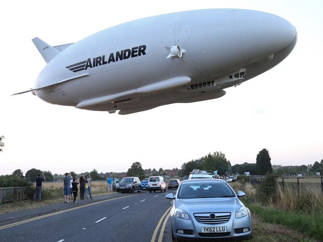 The Hybrid Air Vehicles HAV 304 Airlander 10 hybrid airship is seen in the air over a road on its maiden flight from Cardington Airfield near Bedford, north of London, on August 17, 2016. The Hybrid Air Vehicles 92-metre long, 43.5-metre wide Airlander 10, billed as the world's longest aircraft, lifted off for the first time from an airfield north of London. The Airlander 10 has a large helium-filled fabric hull and is propelled by four turbocharged diesel engines. According to the company it can stay airborne for up to five days at a time if manned, and for over 2 weeks unmanned with a cruising speed of just under 150 km per hour and a payload capacity of up to 10,000 kg. (Photo by JUSTIN TALLIS / AFP)