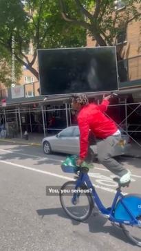 Man rides bike with TV on his head