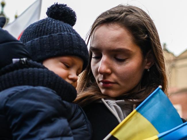 KRAKOW, POLAND - FEBRUARY 20: A woman and her child hold small Ukrainian national flags during a protest for peace in Ukraine at Krakow's UNESCO listed Main Square on February 20, 2022 in Krakow, Poland. For the past days, NATO Defence Ministers have gathered in Brussels to discuss the expansion of military points along the European Eastern flank. Ongoing conversations between Western countries and Russia to de-escalate the crisis at the Russian-Ukrainian border continue, but Western leaders continue to claim that there is a very high chance that a Russian invasion might happen in the coming days. (Photo by Omar Marques/Getty Images)