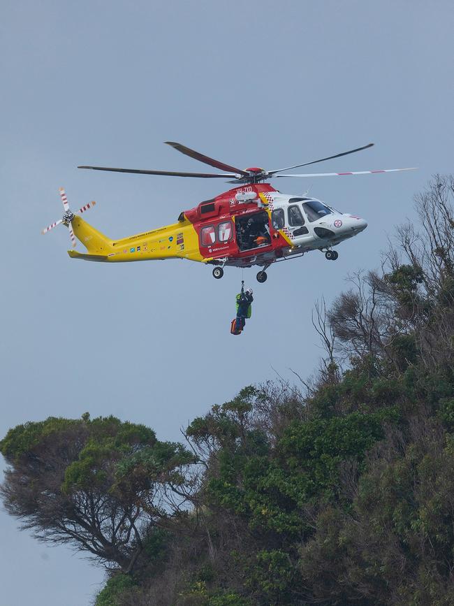 A Westpac Chopper rescue worker is lowered to the rocks. Picture: Shane Chaulker