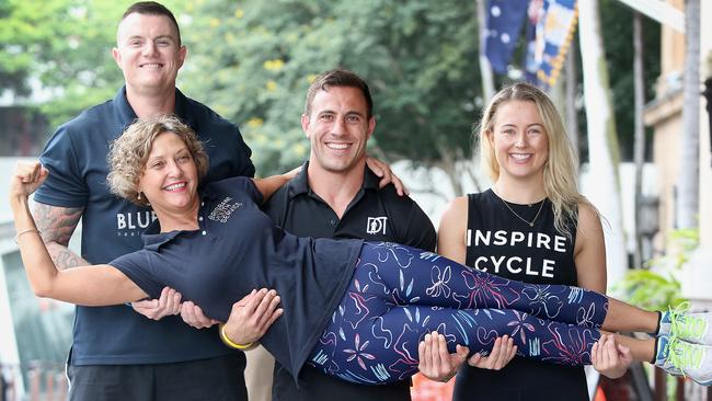 Craig Bridgland, Dave Kramer and Jessie-Kate Bain hold Brisbane Youth Service CEO Annemarree Callander. PICTURE: AAP/Jono Searle