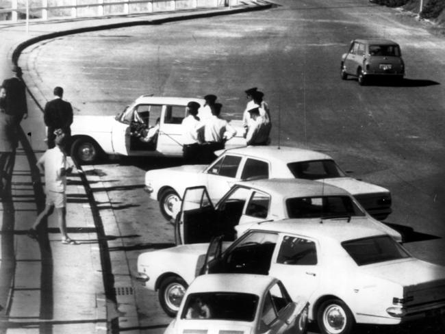 1970: Police inspect the Chrysler Valiant car where the bodies of Raymond Hill, 24, and his girlfriend Irene Rees, 19, were found shot near South Newcastle beach, NSW. The case remains unsolved. File picture