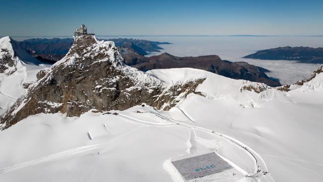 TOPSHOT - An aerial view shows a massive collage of 125,000 drawings and messages from children around the world about climate change seen rolled out on the Aletsch Glacier at an altitude of 3,400 metres near the Jungfraujoch in the Swiss Alps smashing the world record for giant postcards, on November 16, 2018. - The mosaic of postcards, measuring 2,500 square metres (26,910 square feet), was laid out in the snow to "boost a global youth climate movement ahead of the next global climate conference (COP24) in Poland", next month, said the WAVE foundation, which organised the event in cooperation with Swiss authorities. (Photo by Fabrice COFFRINI / AFP)