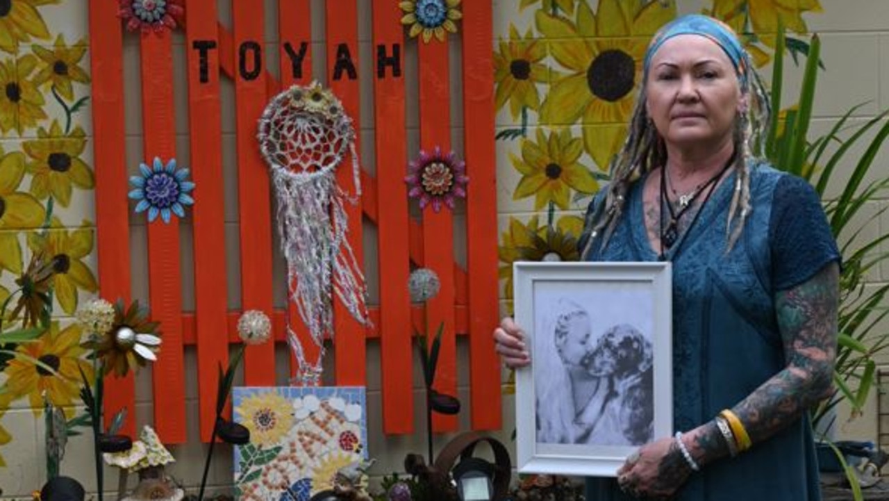 Standing in front of a vibrant memorial adorned with sunflowers and dreamcatchers, Vanessa Gardiner gently holds a framed photograph of her late daughter, Toyah. Picture: Emma Cam.