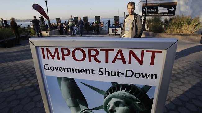 A park ranger, who declined to give his name, reads a sign announcing the closing of the Statue of Liberty.