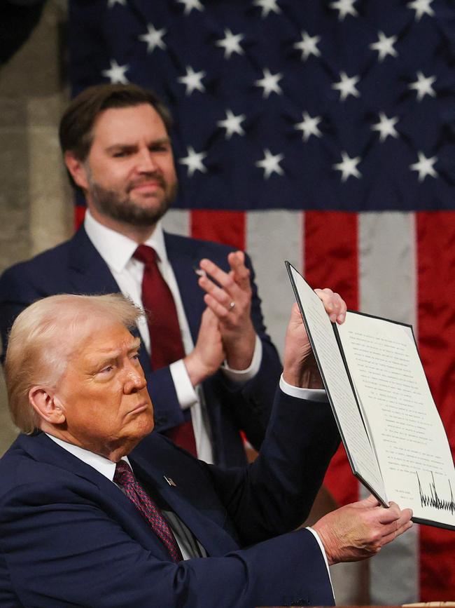 US Vice President JD Vance applauds as US President Donald Trump holds up an executive order.