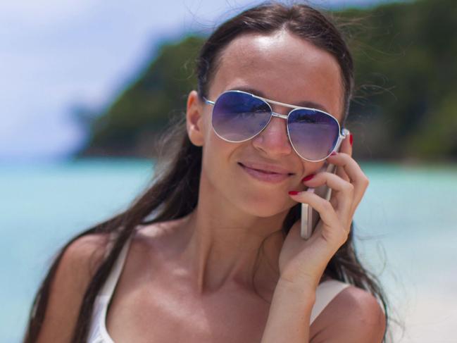 Young beautiful woman at the beach talking on her phone