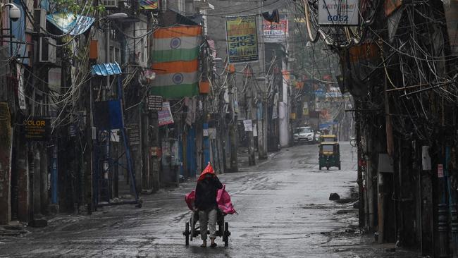 A labourer pulls a cart past closed shops in a deserted street in New Delhi.