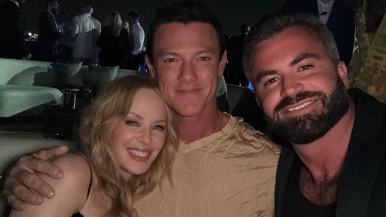 Kylie cuddles up to Luke Evans (centre) and his partner Fran Tomas.