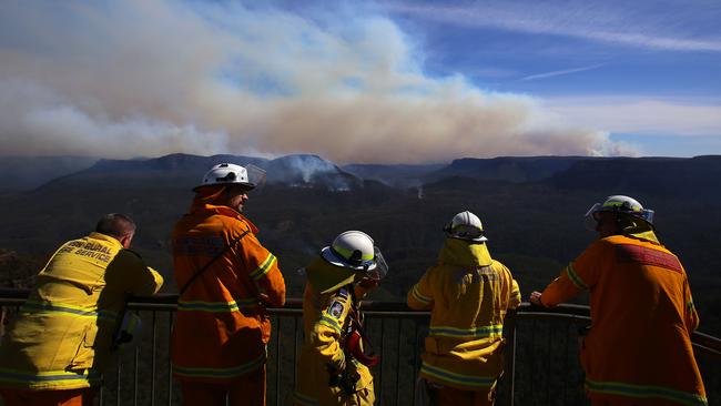 Smoke from the Green Wattle Creek fire is seen in the distance as firefighters from the NSW RFS monitor the remnants of the Ruined Castle fire in the Jamieson valley from Echo Point lookout in Katoomba. Picture: AAP Image/Steven Saphore