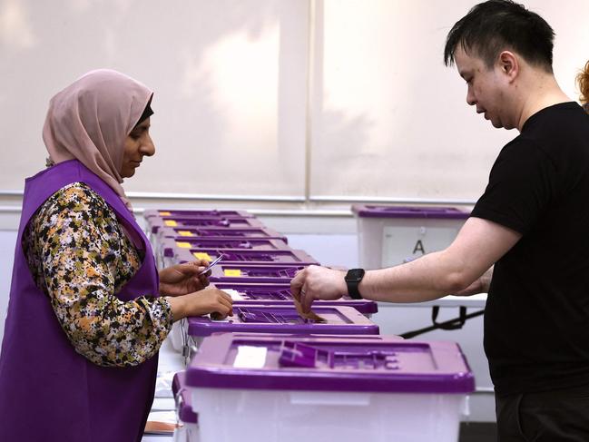 Australian Electoral Commission (AEC) workers assist voters at a voting centre in central Sydney on October 3, 2023. Early voting opened on October 3 across a swathe of Australia on a reform that would recognise Indigenous people in the 1901 constitution for the first time. (Photo by DAVID GRAY / AFP)