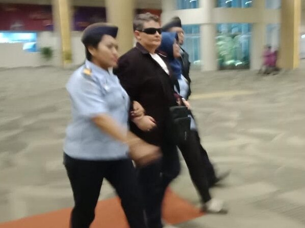 Renae Lawrence is escorted through Bali airport by Immigration officials.