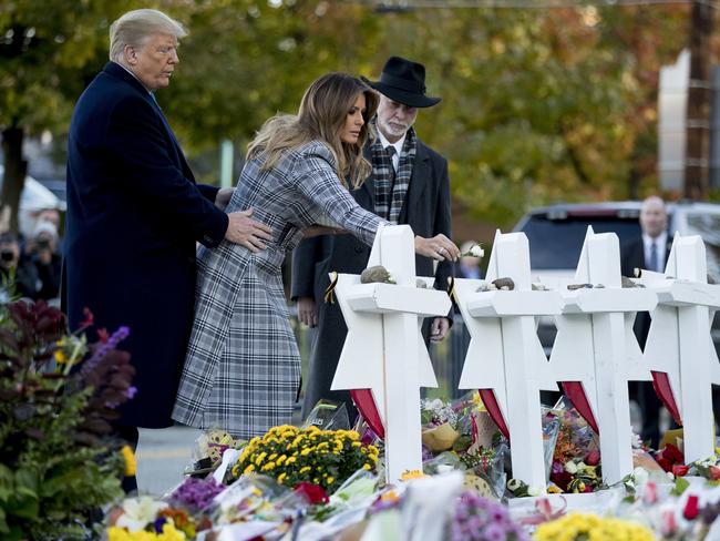 First lady Melania Trump, accompanied by President Donald Trump, and Tree of Life Rabbi Jeffrey Myers, right, puts down a white flower at a memorial for those killed at the Tree of Life Synagogue in Pittsburgh, Tuesday, Oct. 30, 2018. (AP Photo/Andrew Harnik)