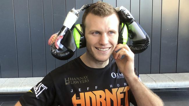 Boxer Jeff Horn wears a pair of boxing gloves on top of earmuffs after his trainer Glenn Rushton discussed biting fears in the pre-fight press conference. (AP Photo/John Pye)