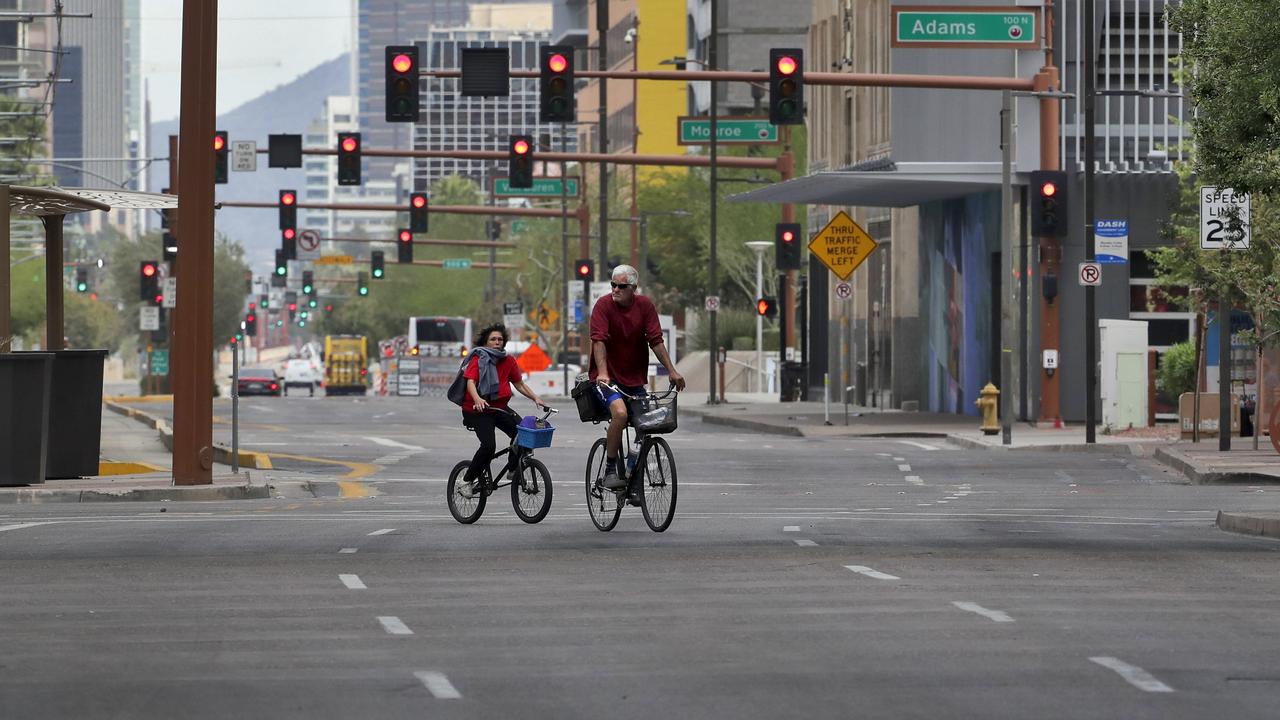 A pair of cyclists navigate an empty street in downtown Phoenix. Picture: Matt York/AP