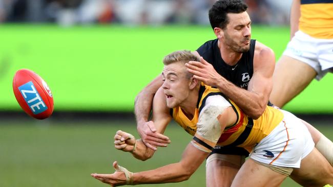 Hugh Greenwood gets a handball away despite pressure from Carlton’s Simon White. Picture: Joe Castro (AAP)