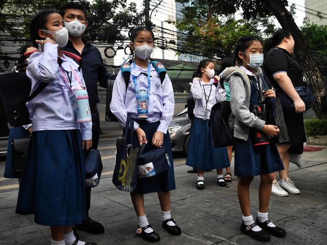 Students in protective face masks arrive outside their school in Bangkok. Picture: Lillian Suwanrumpha/AFP