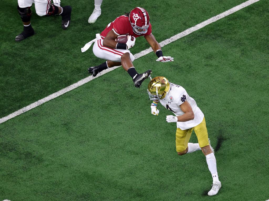 Running back Najee Harris of the Alabama Crimson Tide leaps cornerback Nick McCloud of the Notre Dame Fighting Irish.