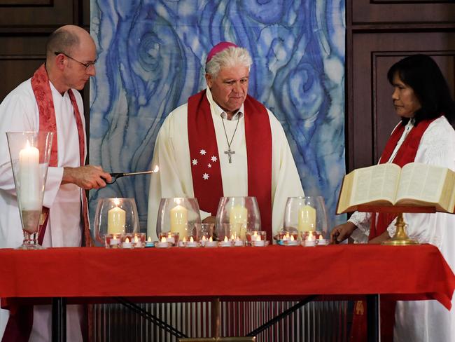 People are seen lighting candles at the Darwin Memorial Uniting Church where a crowd gathered to mourn the death of four men who were allegedly shot dead by Ben Hoffmann. Picture: Keri Megelus