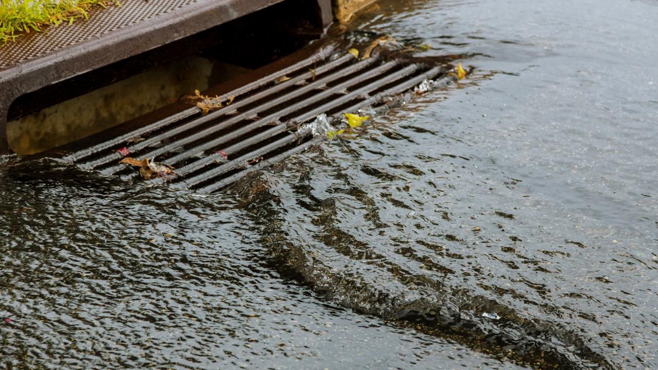 Water gushing from storm sewer following very heavy rainfall of the road after heavy rain.