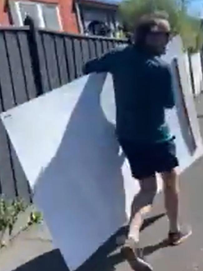 Peter Jordan makes off with a large Amelia Hamer poster in Kooyong. Picture: Supplied