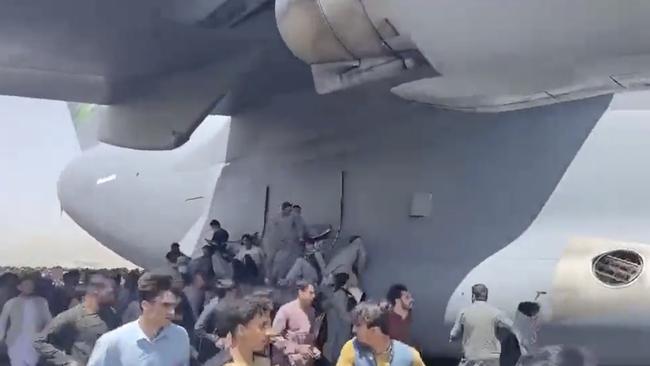 People run on the tarmac at Kabul International Airport as a US military aircraft attempts to take off.