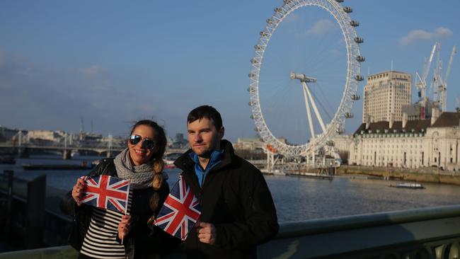 Tourists pose on Westminster Bridge with the London Eye in the background in central London after it reopened.