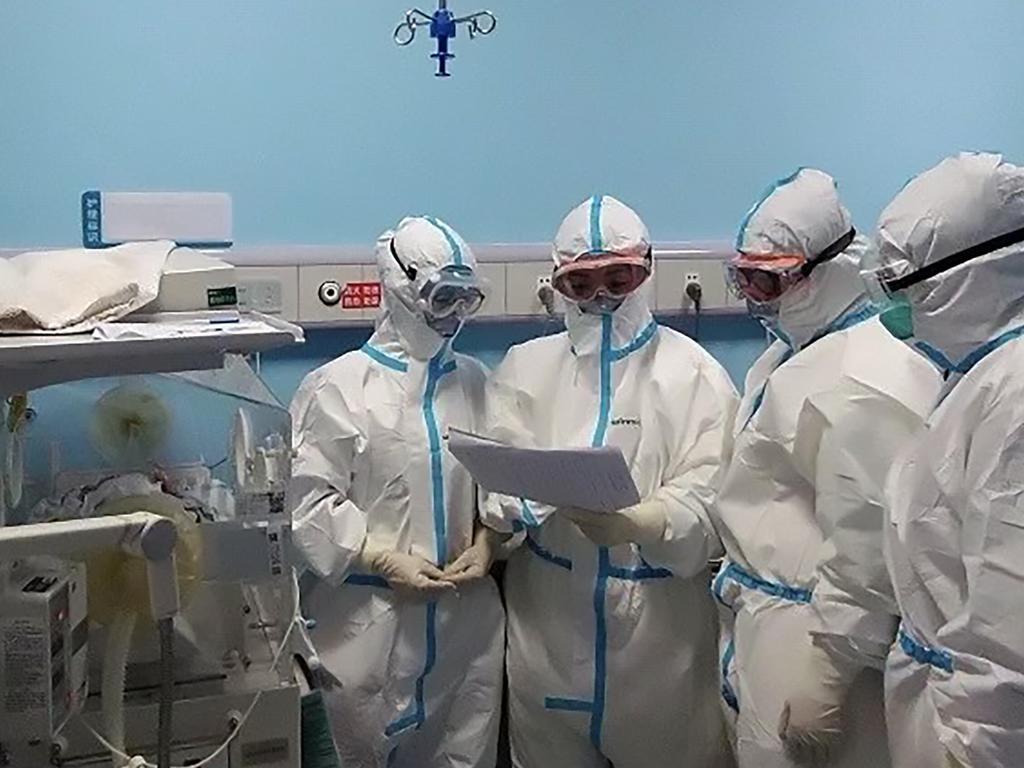 Doctors examine the child's latest health report as she’s given a clean bill of health and discharged from hospital at the age of just 17 days. Picture: Wuhan Children's Hospital/Asiawire/australscope