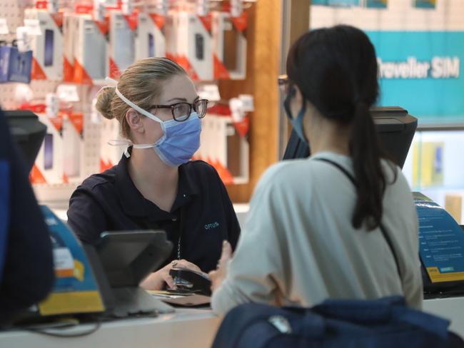 Airport staff with masks on serving passengers from the flight. People arrive from Shanghai into Brisbane International Airport. Pic Peter Wallis