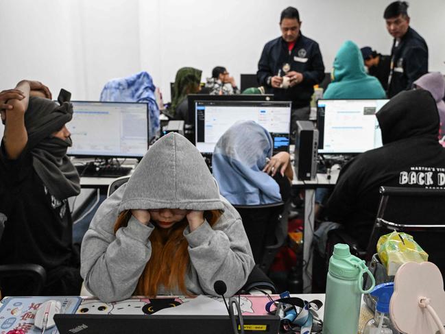 TOPSHOT - Workers sit at their desks during a raid by agents of the Presidential Anti-Organised Crime Commission (PAOCC) and the National Bureau of Investigation at an office of a suspected online scam farm in Manila on January 31, 2025. Philippine authorities arrested around 100 people on January 31 in a raid on a suspected online scam farm in Manila they said extorted victims. (Photo by JAM STA ROSA / AFP)