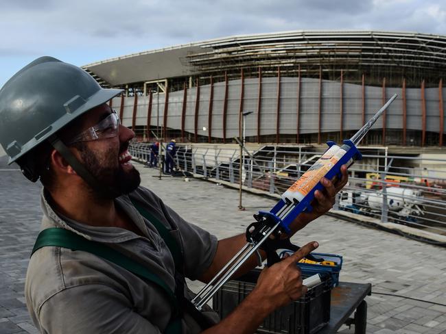 A worker poses for a photo at the construction site of the Olympic Park for the Rio 2016 Olympic games in Rio de Janeiro, Brazil, on October 6, 2015. AFP PHOTO / CHRISTOPHE SIMON