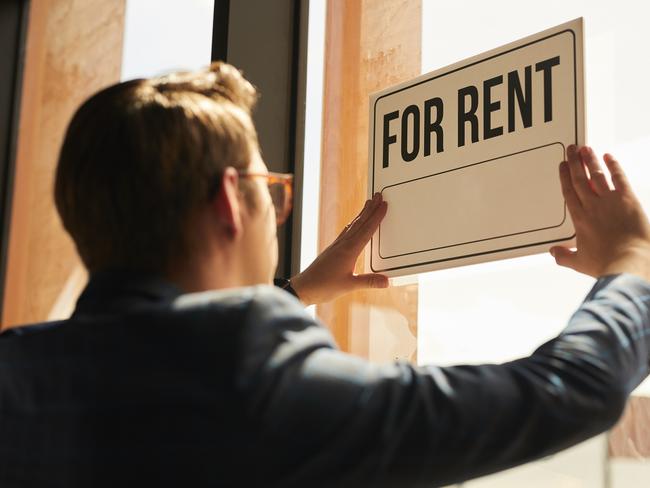 Back view at real estate agent hanging FOR RENT sign on window of house or apartment, copy space