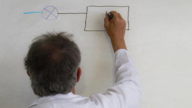 back view of senior teacher writing on white board