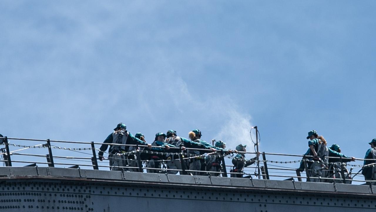 Sydney Harbour Bridge climbers cool down with a blast from a “water mister”. Picture: Julian Andrews