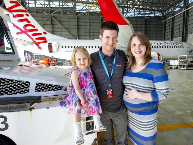 Tony Hill with daughter Stella and wife Hannah in the Virgin Australia hangar at Brisbane Airport.