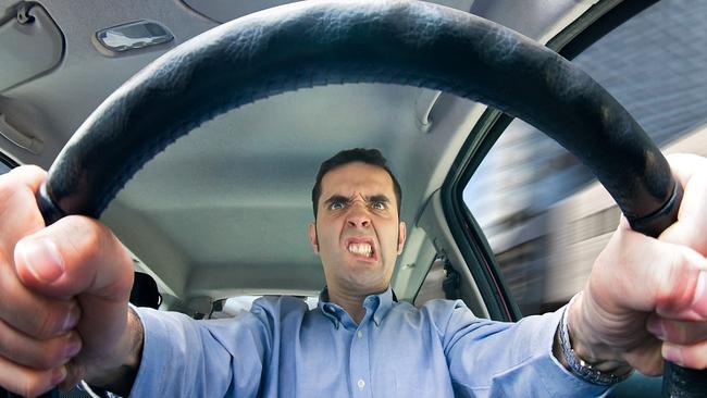 A furious man driving, as seen from behind the wheel. Shot using a very wide fisheye lens focused on the driver's face.