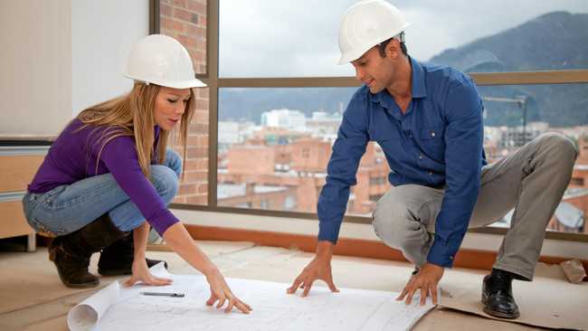 Architects at a construction site looking at the blueprints. Picture: andresrimaging