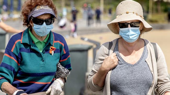 Walkers wearing face masks at Elwood Beach. Picture: David Geraghty