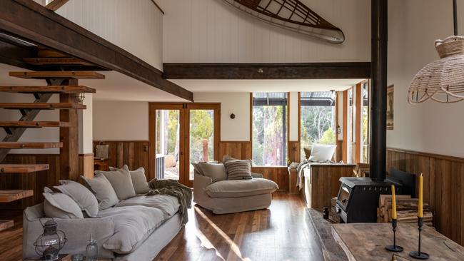 The Voyager’s sunny, open-plan living area features warm timbers and is made cosy with deep, soft sofas with plump cushions and a freestanding wood heater. Picture: Supplied.