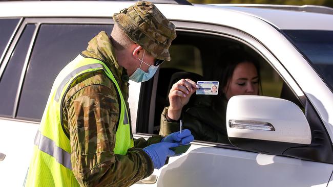 An Australian Defence Force member inspects a licence at a vehicle checkpoint on the Princes Highway at Little River. Picture: NCA NewsWire / Ian Currie