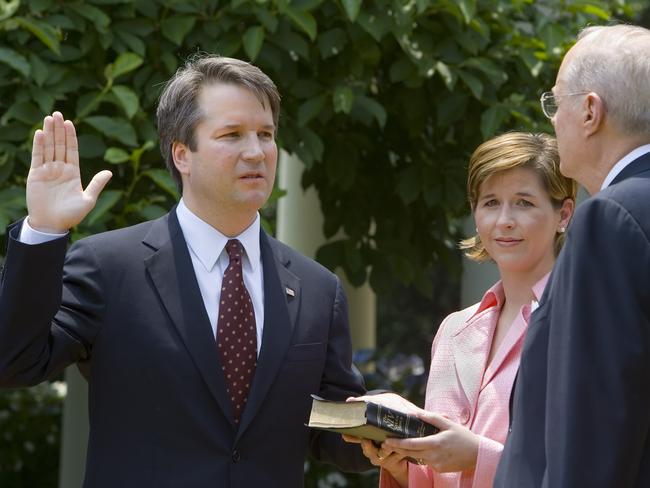 (FILES) In this file photo taken on June 01, 2006 Brett Kavanaugh (L) is sworn in as a US Court of Appeals Judge for the District of Columbia by US Supreme Court Justice Anthony Kennedy (R) as Kavanaugh's wife Ashley (C) holds the Bible during ceremonies 01 June 2006 in the Rose Garden of the White House in Washington, DC.  President Donald Trump will announce his US Supreme Court pick Monday July 9, an intensely anticipated decision likely to swing the bench rightward for years to come and which has Washington readying for an explosive confirmation battle. / AFP PHOTO / Paul J. RICHARDS