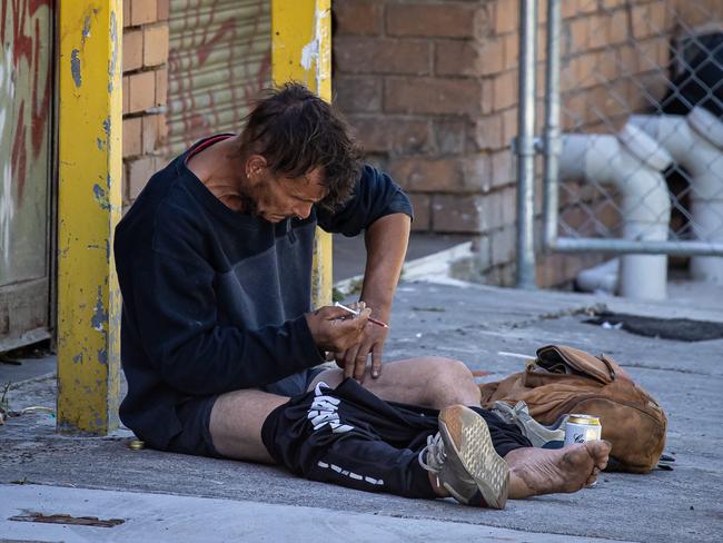 A man openly injects drugs into his leg in a thoroughfare alley. Picture: Jason Edwards