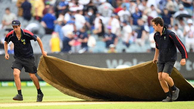 Grounds keepers put out the covers as rain falls on day four. Picture: AAP.