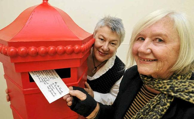 BACK IN TIME: ‘Posting’ a postcard to her 16-year-old self, Federal artist Jill Keogh, is watched by Christine Minkov, curator of the exhibition. Picture: Cathy Adams