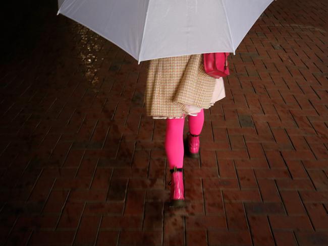 A racing fan arrives early under the cover of an umbrella. Picture: Getty