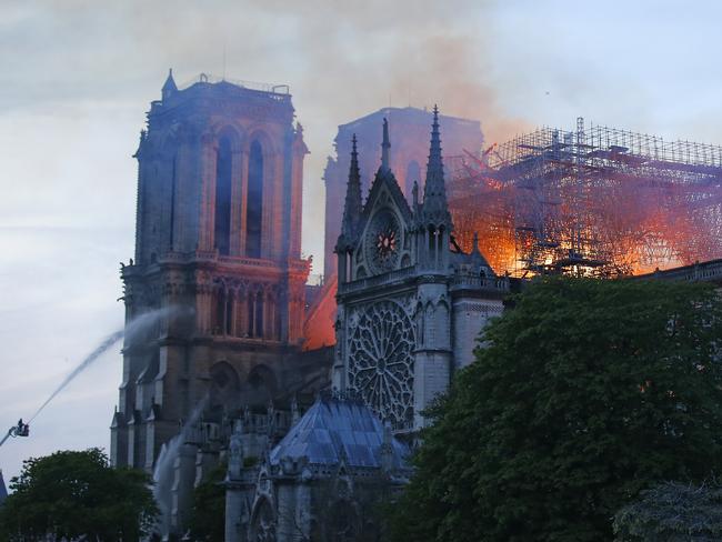 A firefighter tackles the blaze as flames and smoke rise from Notre Dame cathedral as it burns in Paris, Monday, April 15, 2019. (AP Photo/Michel Euler)